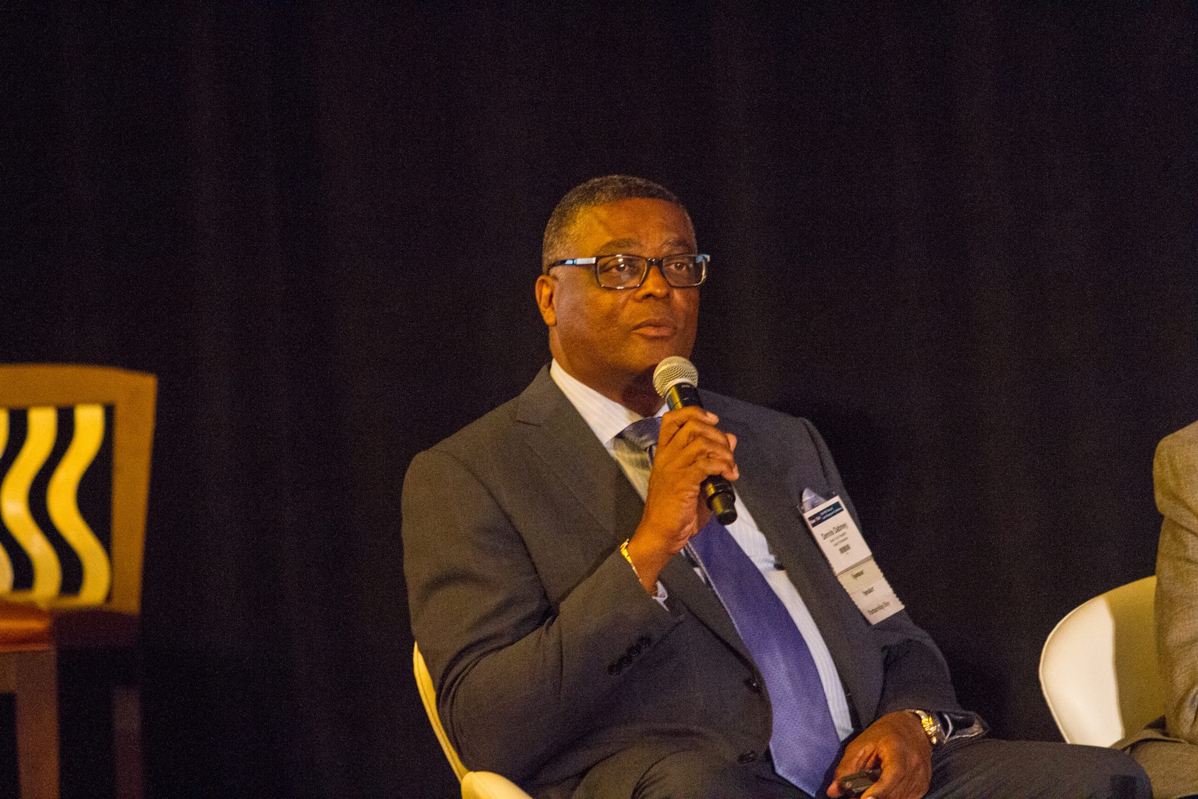 Dennis Dabney seated on stage, speaking into a microphone