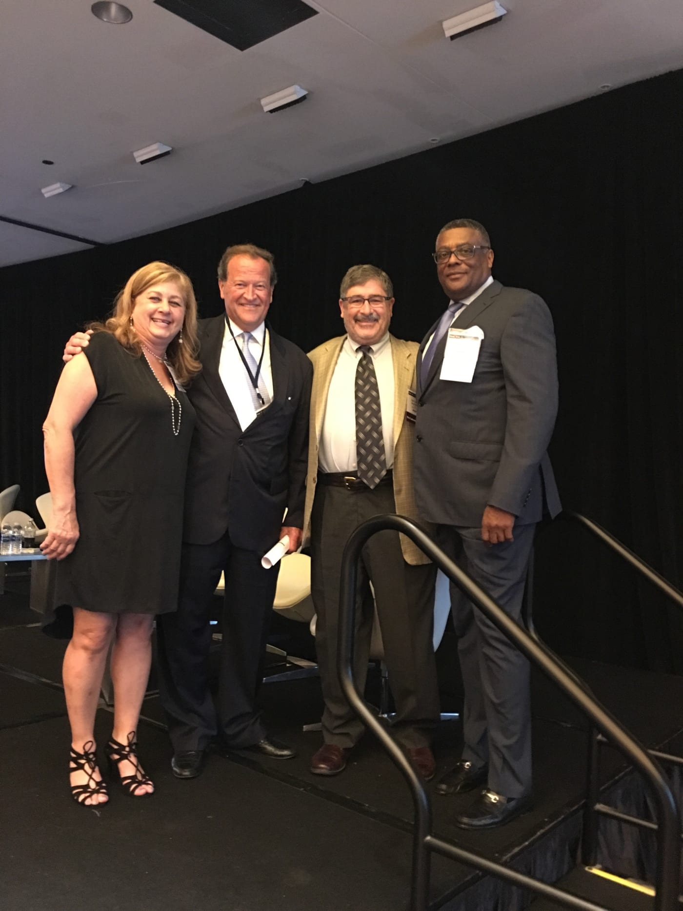 Dennis Dabney standing with colleagues beside a stage staircase